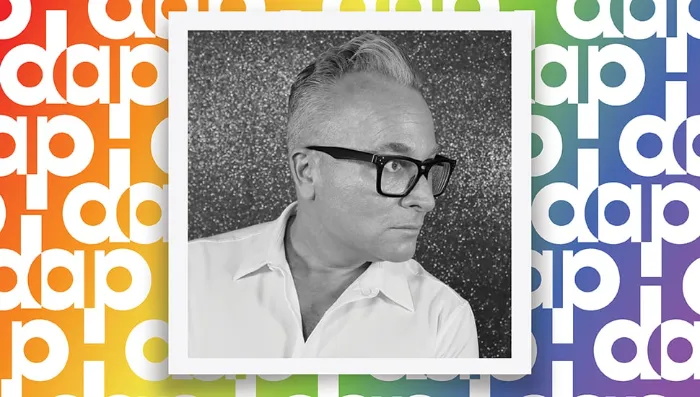 A black-and-white photo of Steven Henke, with light hair, glasses, and a collared shirt, is centered against a colorful "dap" patterned background in shades of orange, yellow, green, blue, and purple. The person is looking to the right.