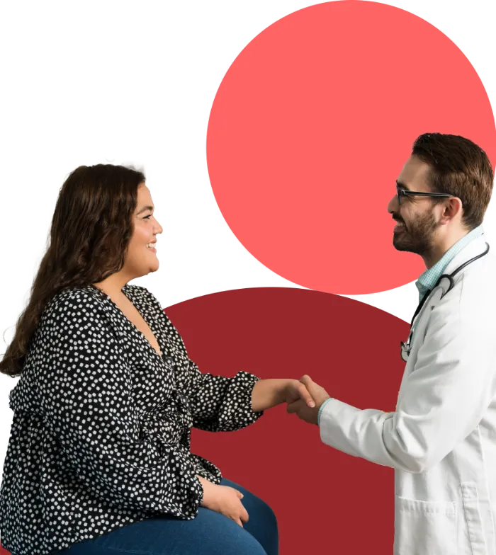 A female patient in a black and white polka dot blouse sits, smiling and holding hands with a male doctor in a white coat and stethoscope. Both appear happy. The background features large red circles.