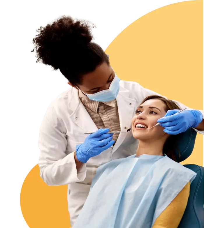A female dentist wearing a mask, white coat, and blue gloves examines a smiling female patient in a dental chair. The dentist holds dental tools and the patient wears a protective bib. The background features a yellow abstract shape.
