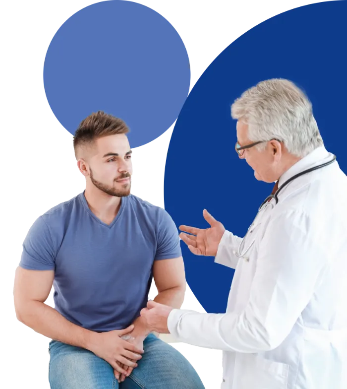 A male doctor in a white coat talks to a young man in a blue t-shirt, who is seated and listening attentively. The background features two solid blue circles of different sizes.