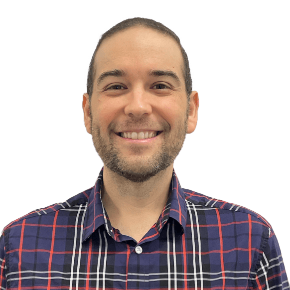 A smiling man with short brown hair and a trimmed beard wears a blue, red, and white plaid shirt. He is facing the camera against a plain white background. His expression appears friendly and approachable.